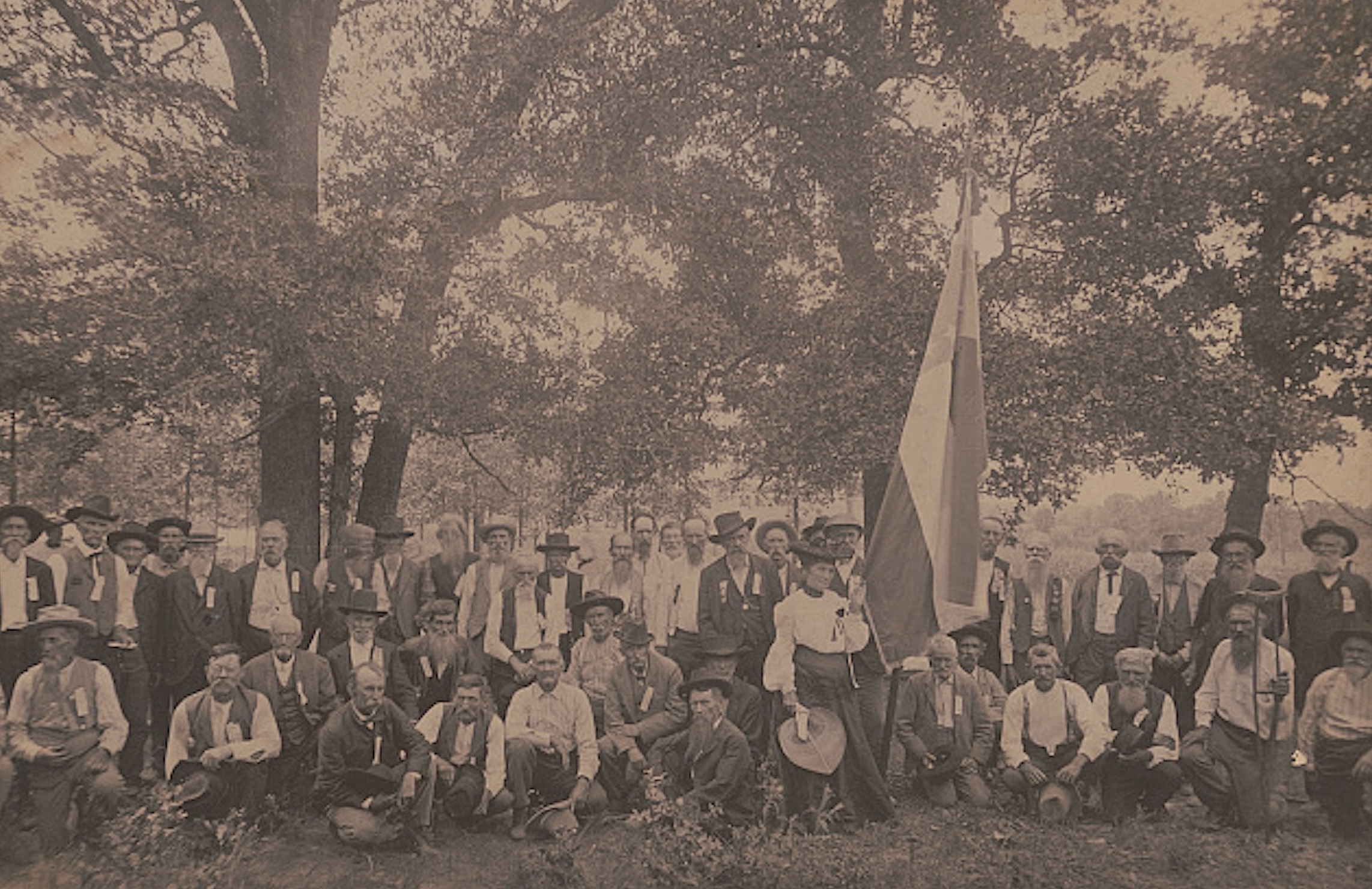 A woman holds the first Confederate national flag at a gathering of unidentified Civil War veterans around 1900.